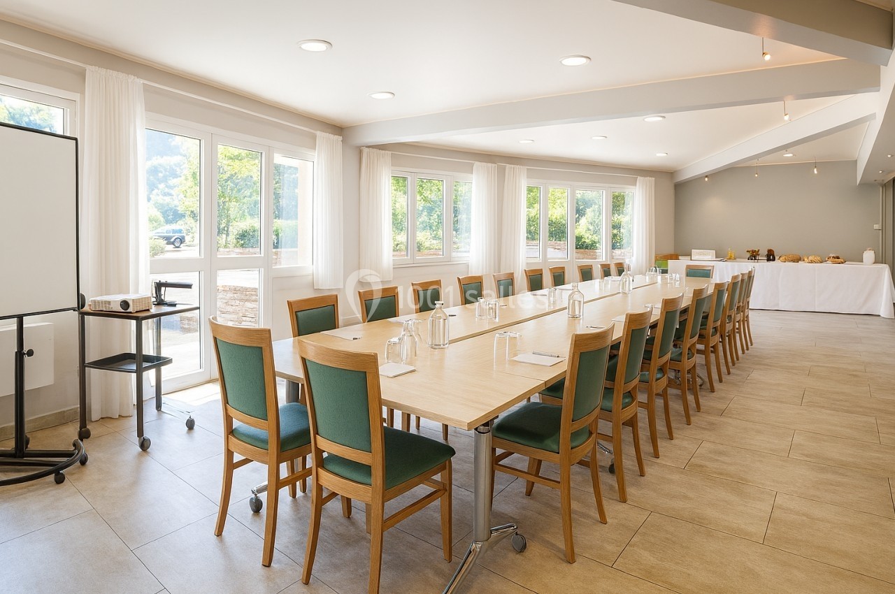 Salle de réunion lumineuse avec une grande table rectangulaire entourée de chaises, équipée d'un tableau et d'un…