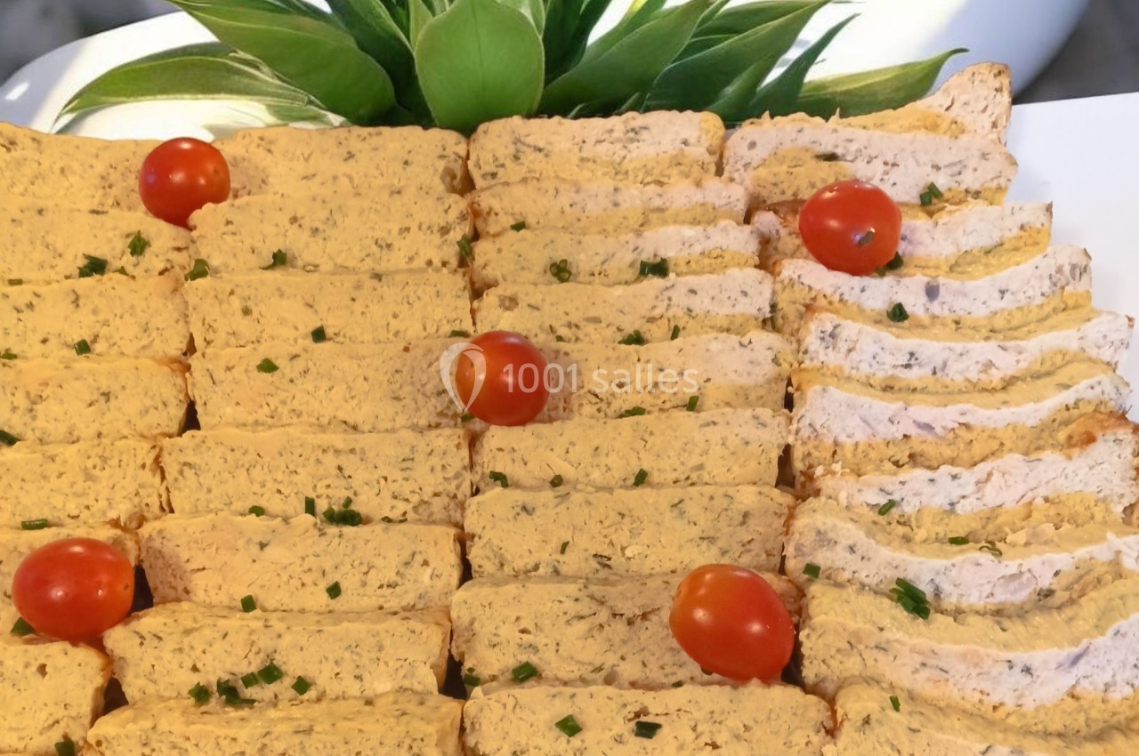 Tranches de terrine aux herbes garnies de tomates cerises et de ciboulette, présentées sur un plateau.