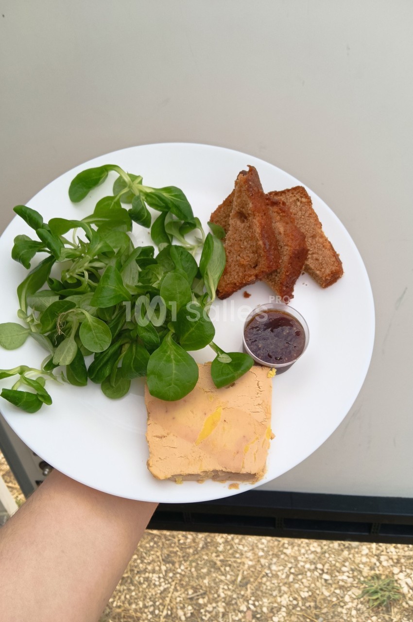 Assiette contenant du foie gras, de la mâche, des tranches de pain grillé et une petite portion de confiture.
