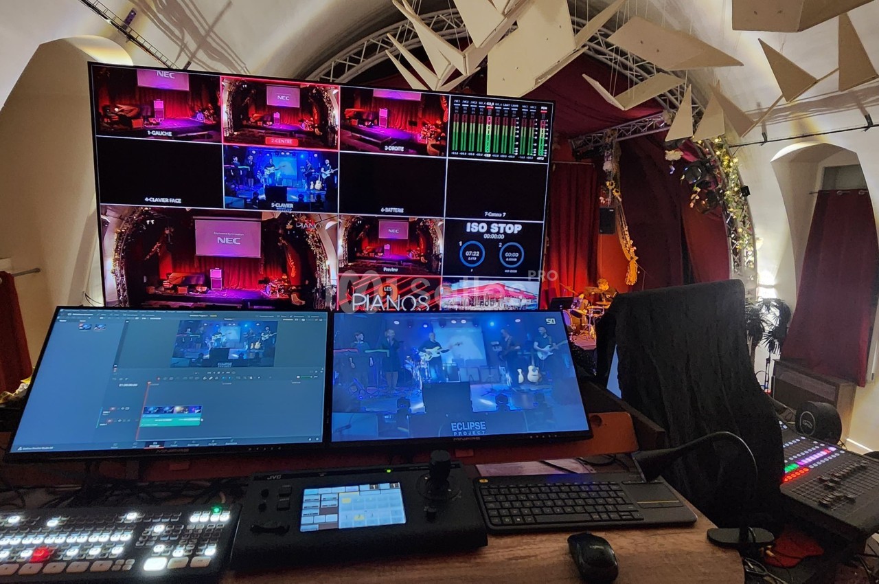 Poste de régie audiovisuelle avec plusieurs écrans affichant des flux vidéo en direct dans une salle décorée.