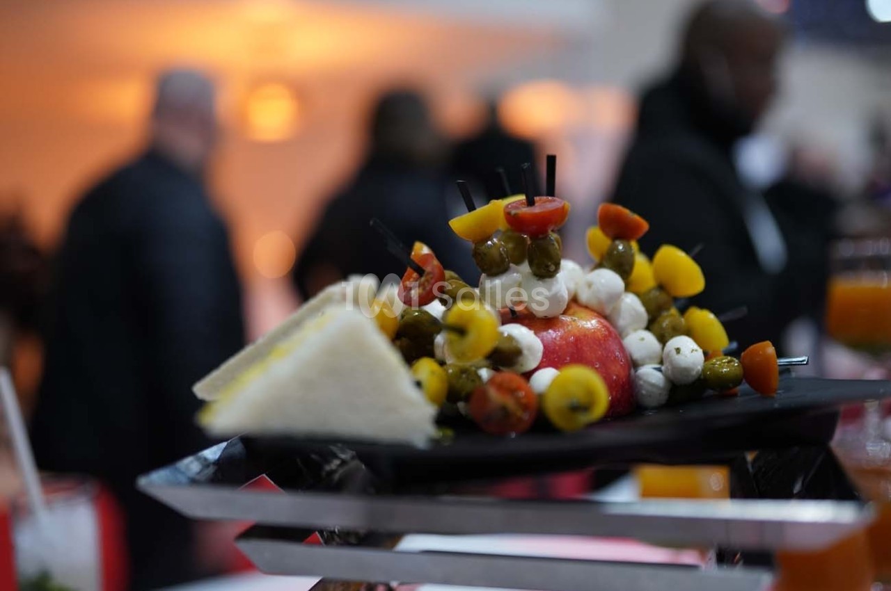 Assiette de présentation avec brochettes de tomates, billes de mozzarella, câpres et tranches de pain triangulaires.