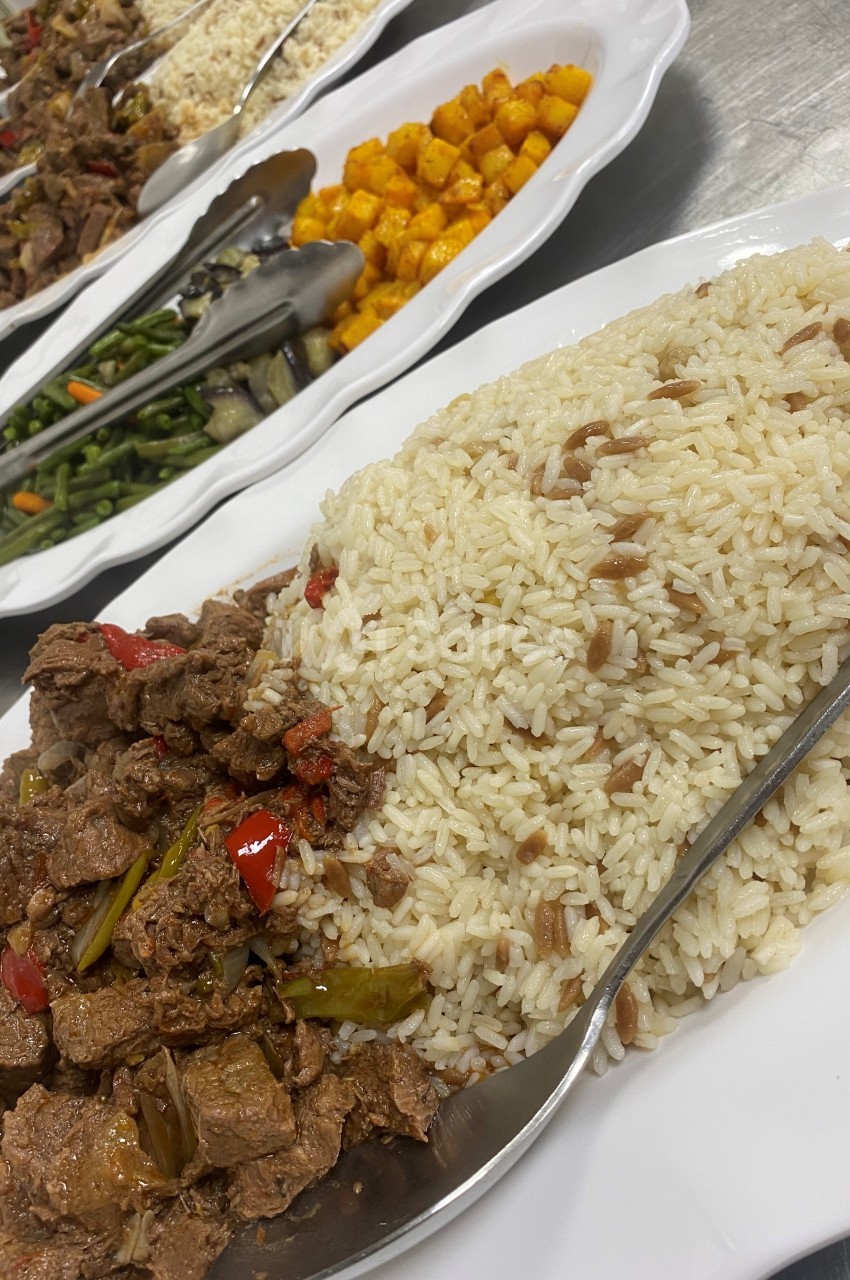 Assortiment de plats comprenant du riz, des légumes sautés, des morceaux de viande et des pommes de terre rôties.