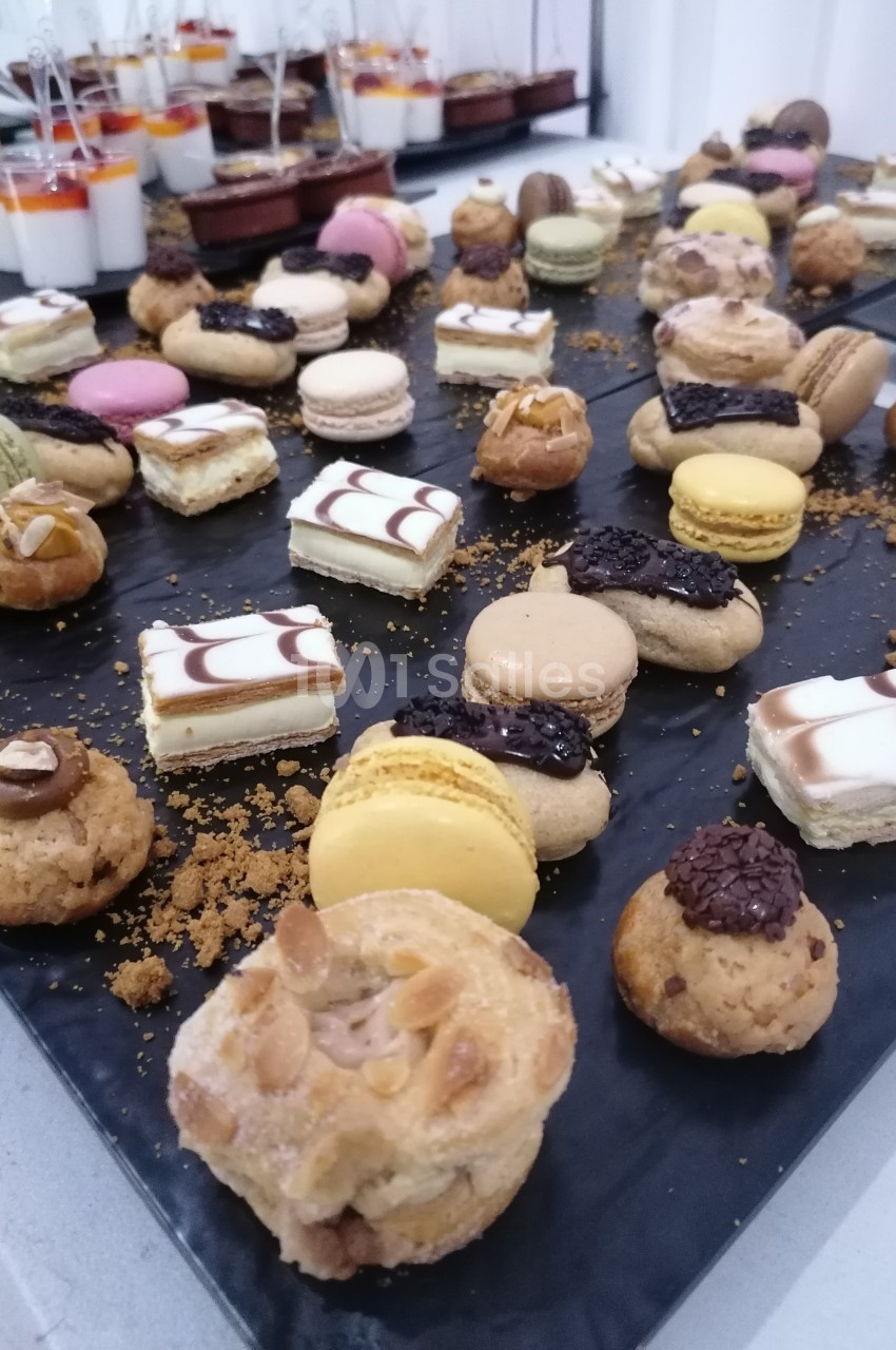 Plateau de pâtisseries variées comprenant macarons, éclairs, choux garnis et autres desserts disposés sur une table.