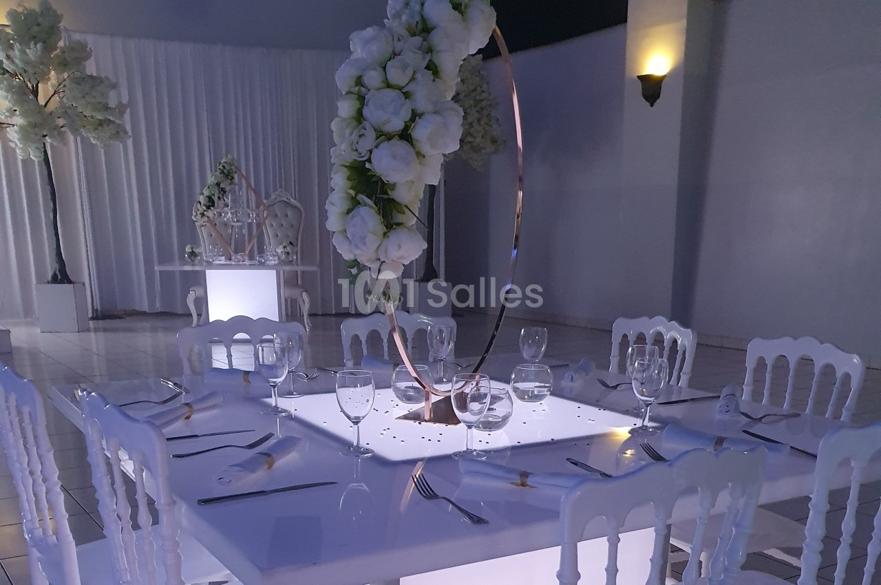 Table élégamment dressée avec des assiettes, verres et couverts, décorée de fleurs blanches sur un anneau doré.