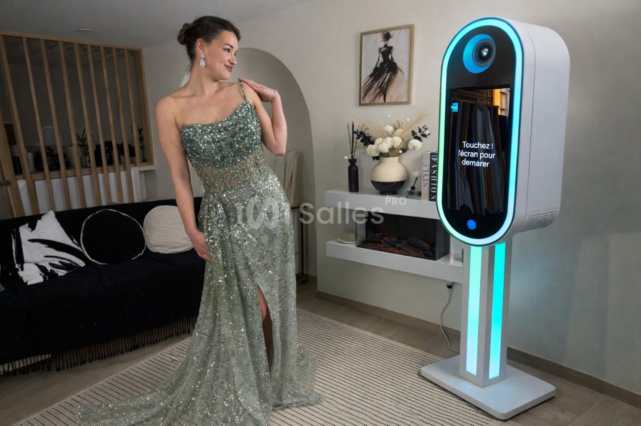 Une femme en robe de soirée verte pose près d'une borne photo interactive dans un salon moderne.