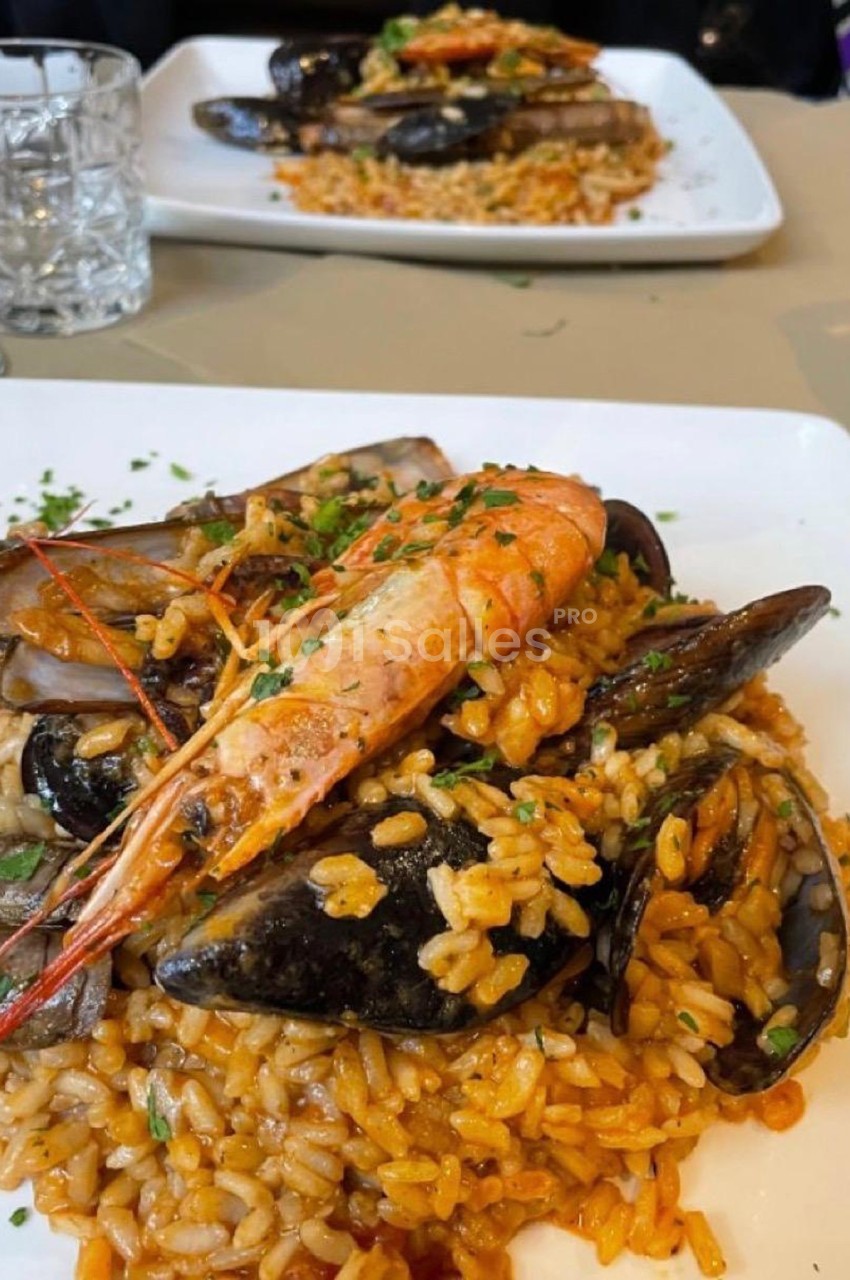 Assiette de riz cuisiné avec des fruits de mer variés, dont crevettes, moules et couteaux, garnie de persil.