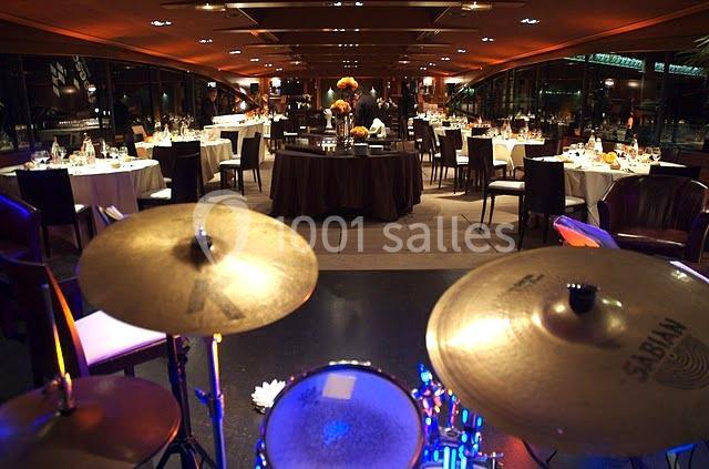 Salle de restaurant élégante avec tables dressées, vue depuis une batterie au premier plan.