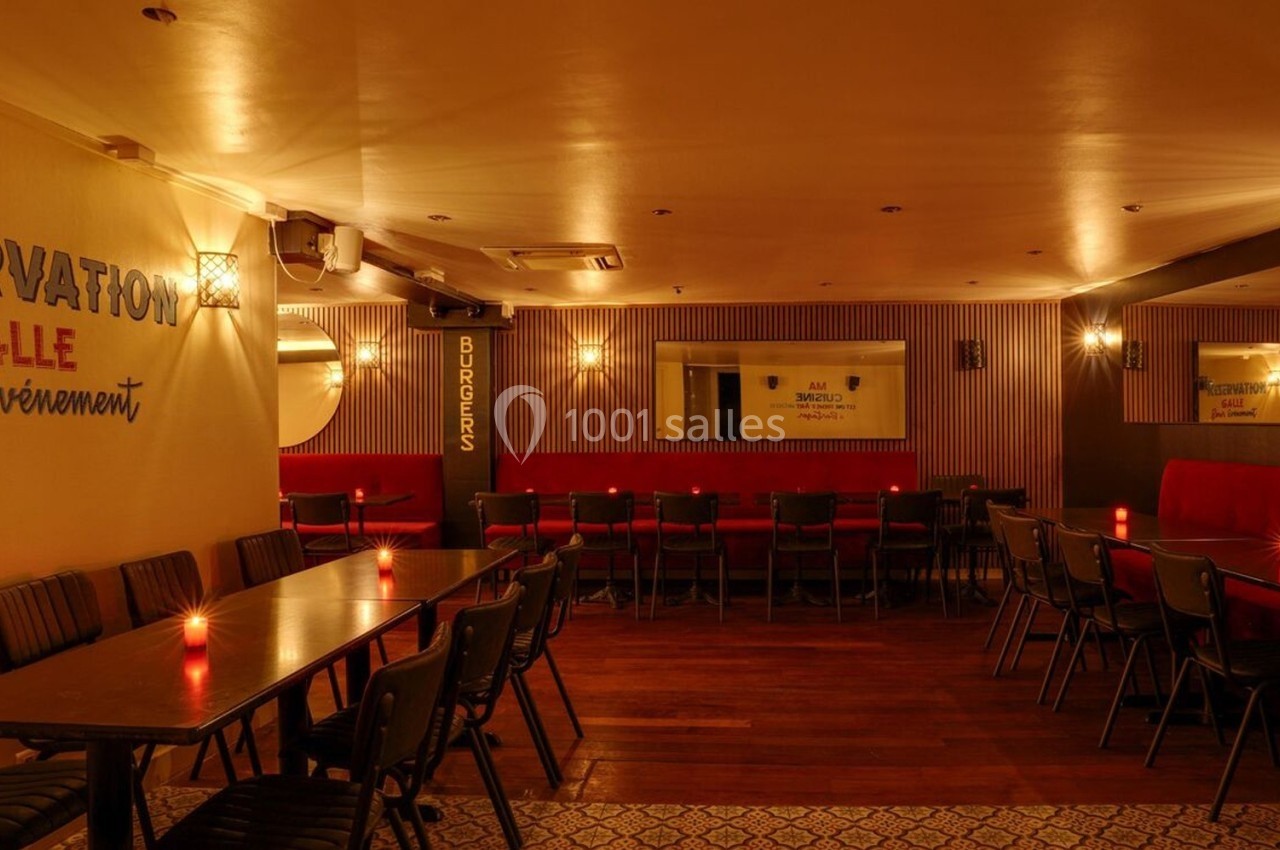 Salle de restaurant chaleureuse avec éclairage tamisé, tables alignées et inscriptions murales décoratives.
