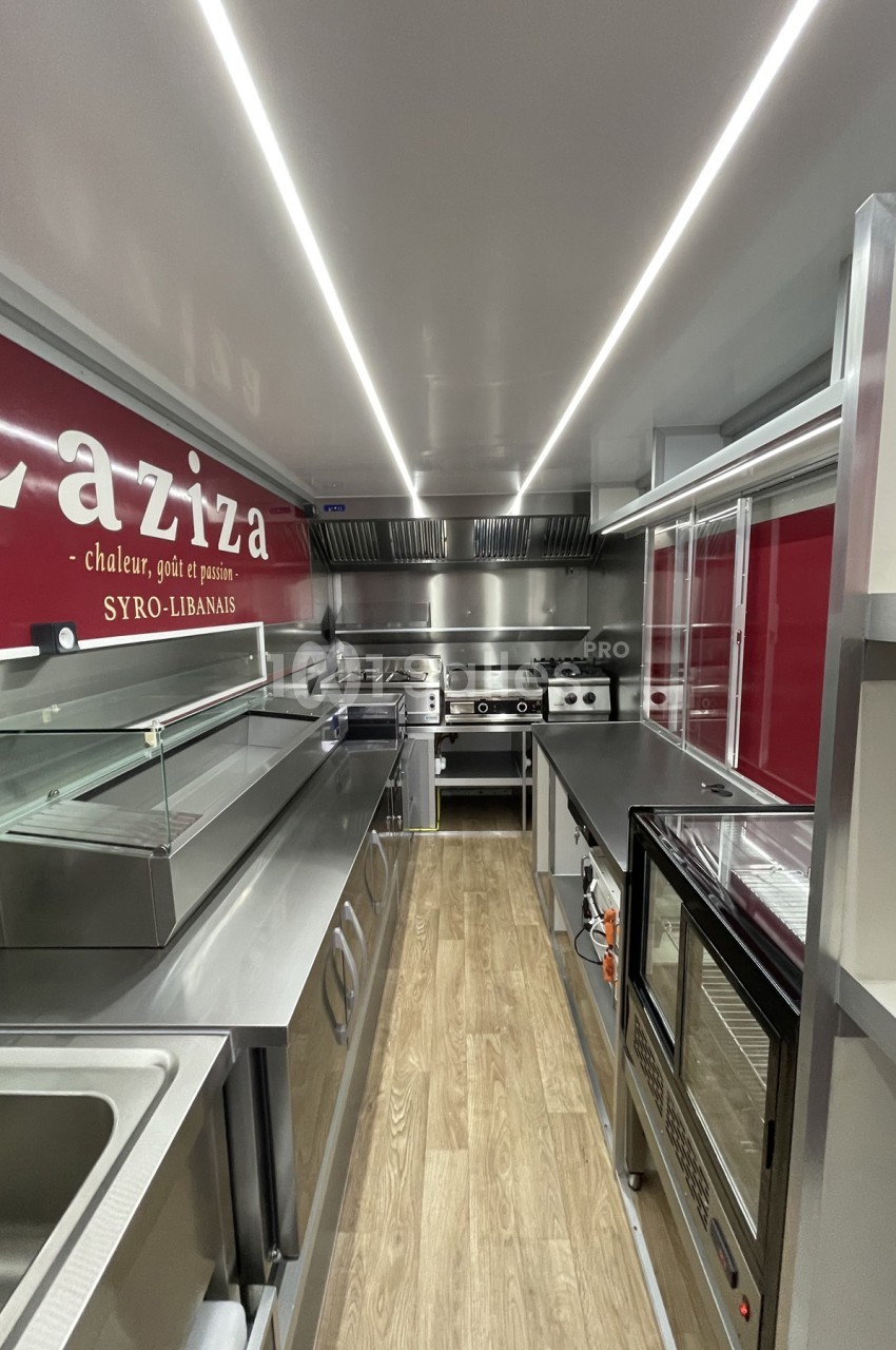 Intérieur d'une cuisine professionnelle moderne avec équipements en inox et plancher en bois clair.