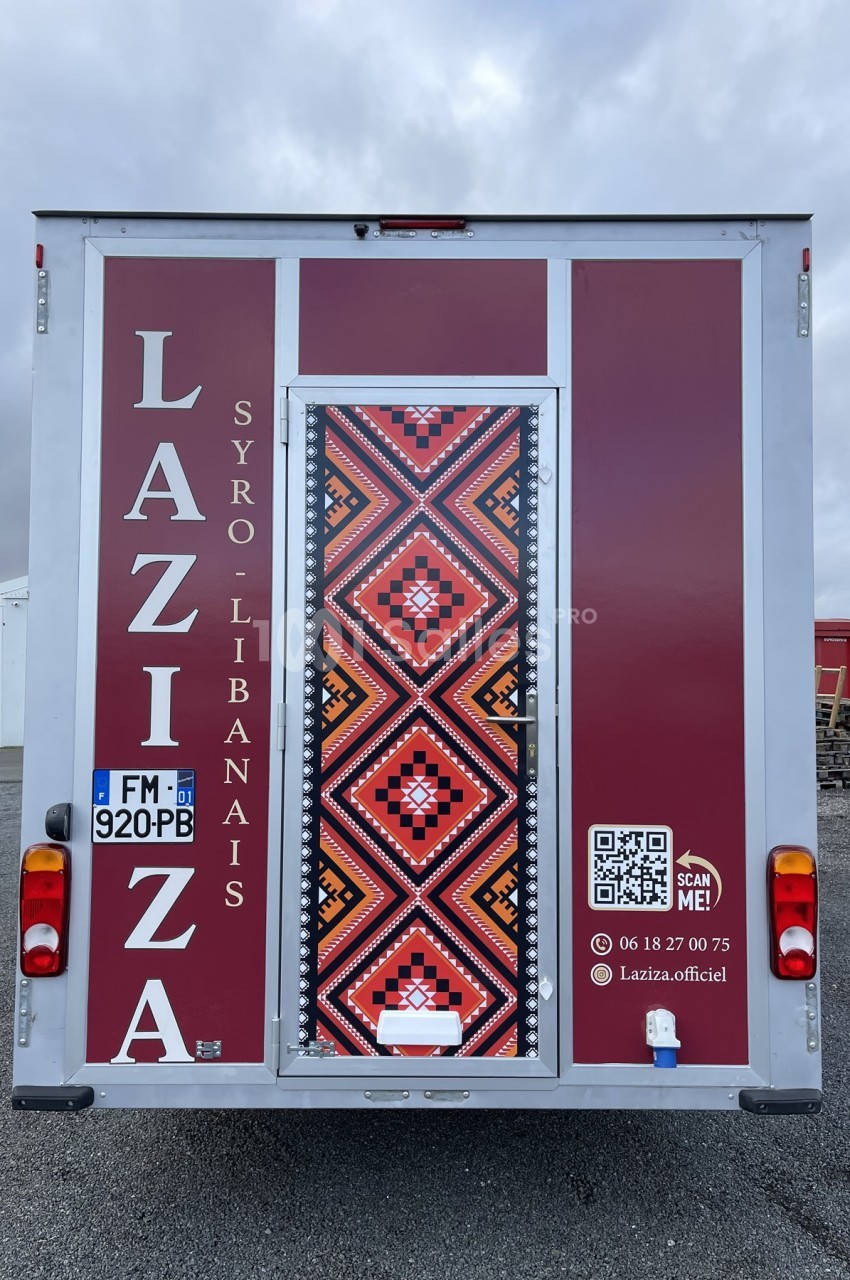 Vue arrière d'un food truck syro-libanais rouge avec motifs géométriques et coordonnées de contact affichées.