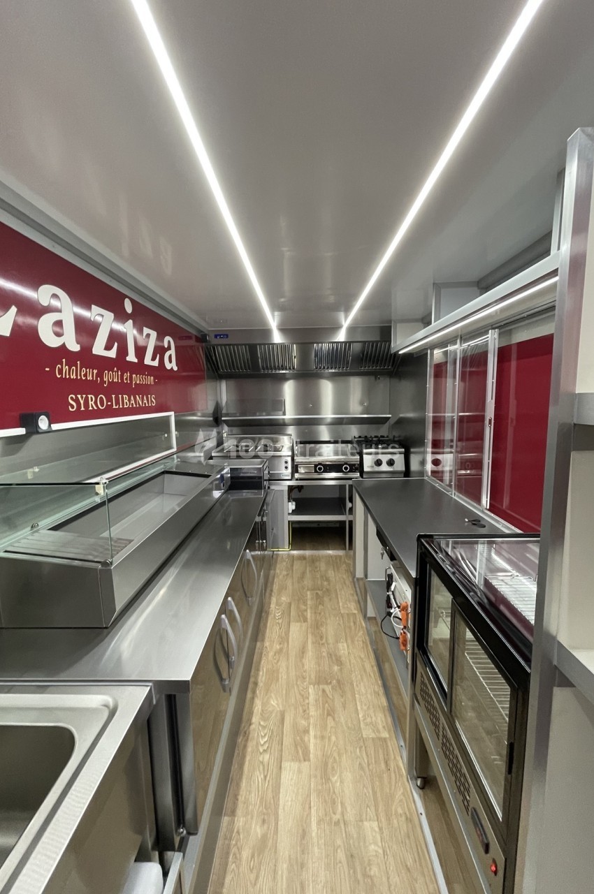 Intérieur d'un food truck moderne avec équipements de cuisine en inox et plancher en bois clair.