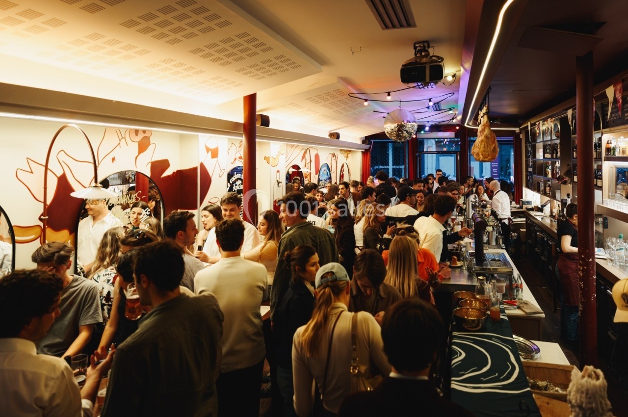 Un bar animé rempli de personnes discutant et partageant un moment convivial dans un décor moderne et coloré.