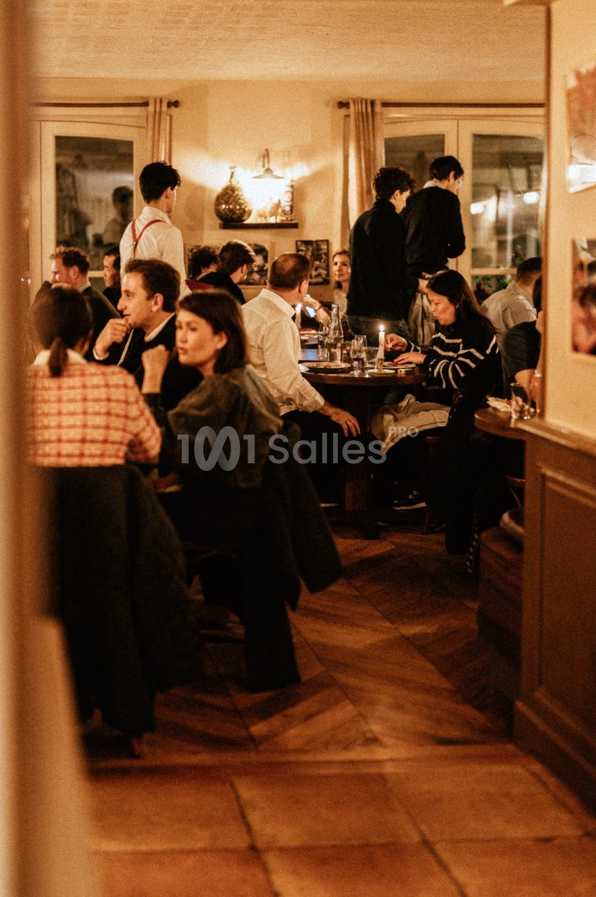 Salle de restaurant animée avec des clients attablés et des serveurs en service dans une ambiance chaleureuse.