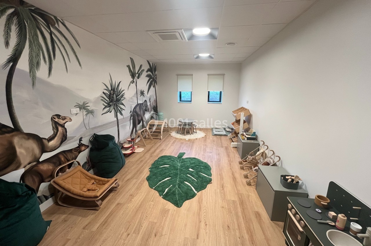 Salle de jeux pour enfants avec décor mural de jungle, tapis en forme de feuille et mobilier en bois.