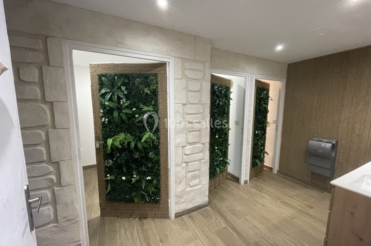 Vue d'un espace intérieur avec des portes décorées de murs végétaux et un sol en bois clair.