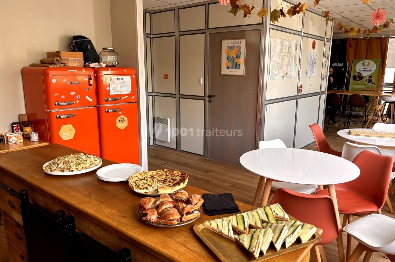 Buffet avec viennoiseries, quiches et sandwichs dans une salle décorée avec des tons automnaux.