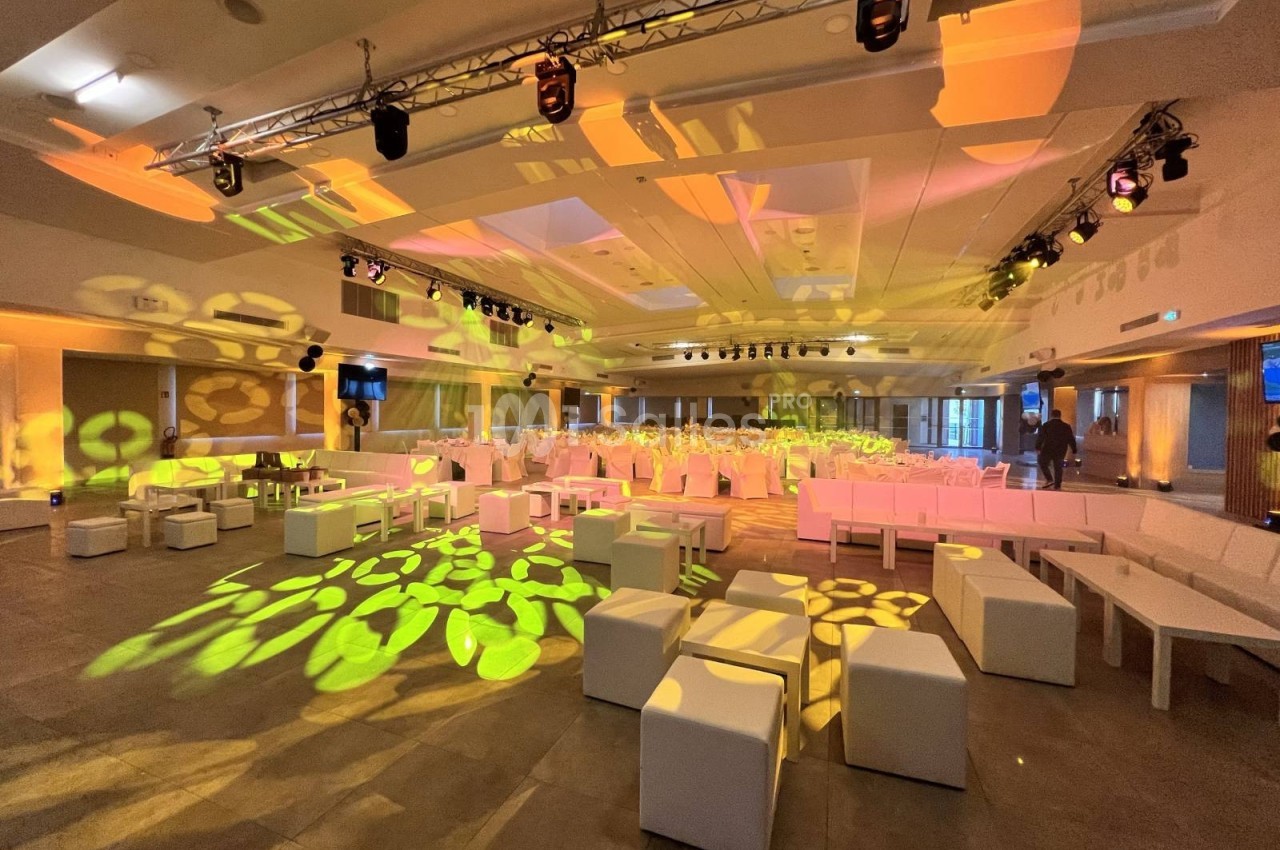 Salle de réception moderne avec éclairage coloré, sièges blancs et décorations lumineuses au sol.