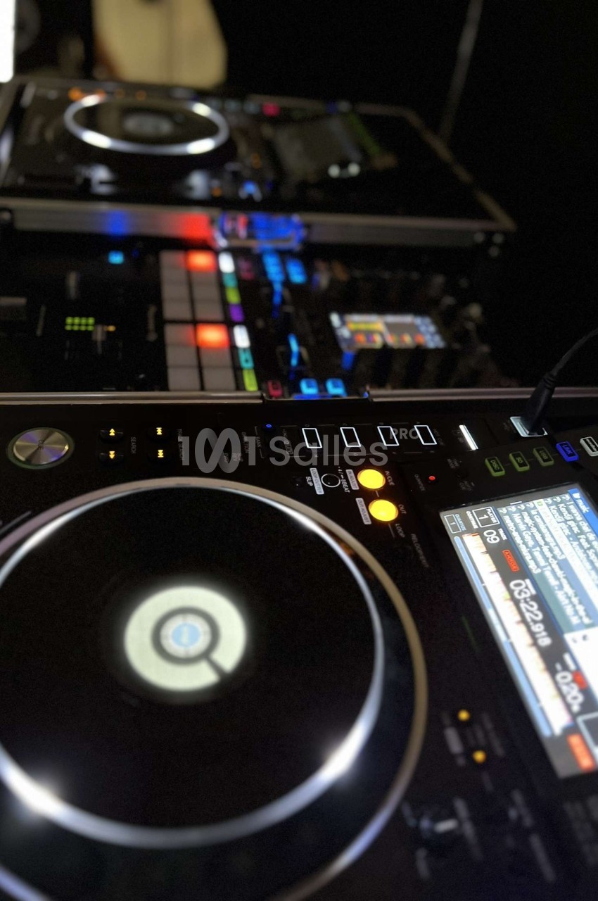 Deux platines DJ et une table de mixage éclairées, avec des boutons et écrans lumineux en gros plan.