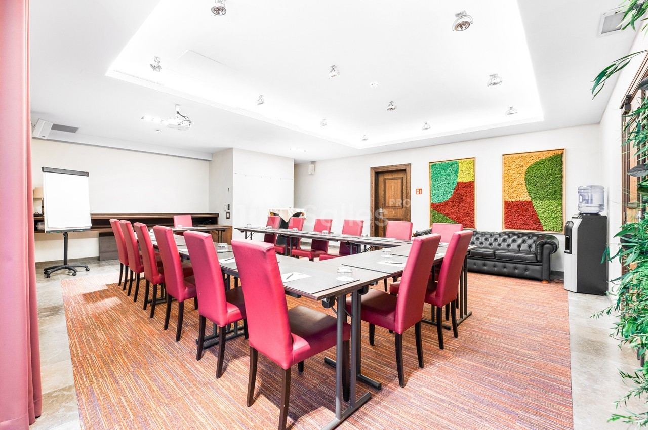 Salle de réunion lumineuse avec des chaises rouges, une grande table, un tableau de conférence et des décorations murales…