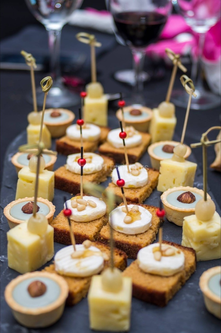 Plateau de bouchées apéritives variées, incluant fromage, tartelettes et toasts, sur une table dressée.