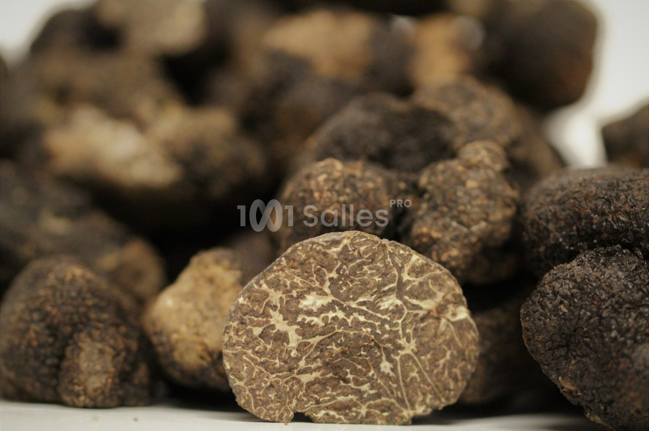Truffes noires entières avec une coupe montrant leur texture intérieure marbrée.