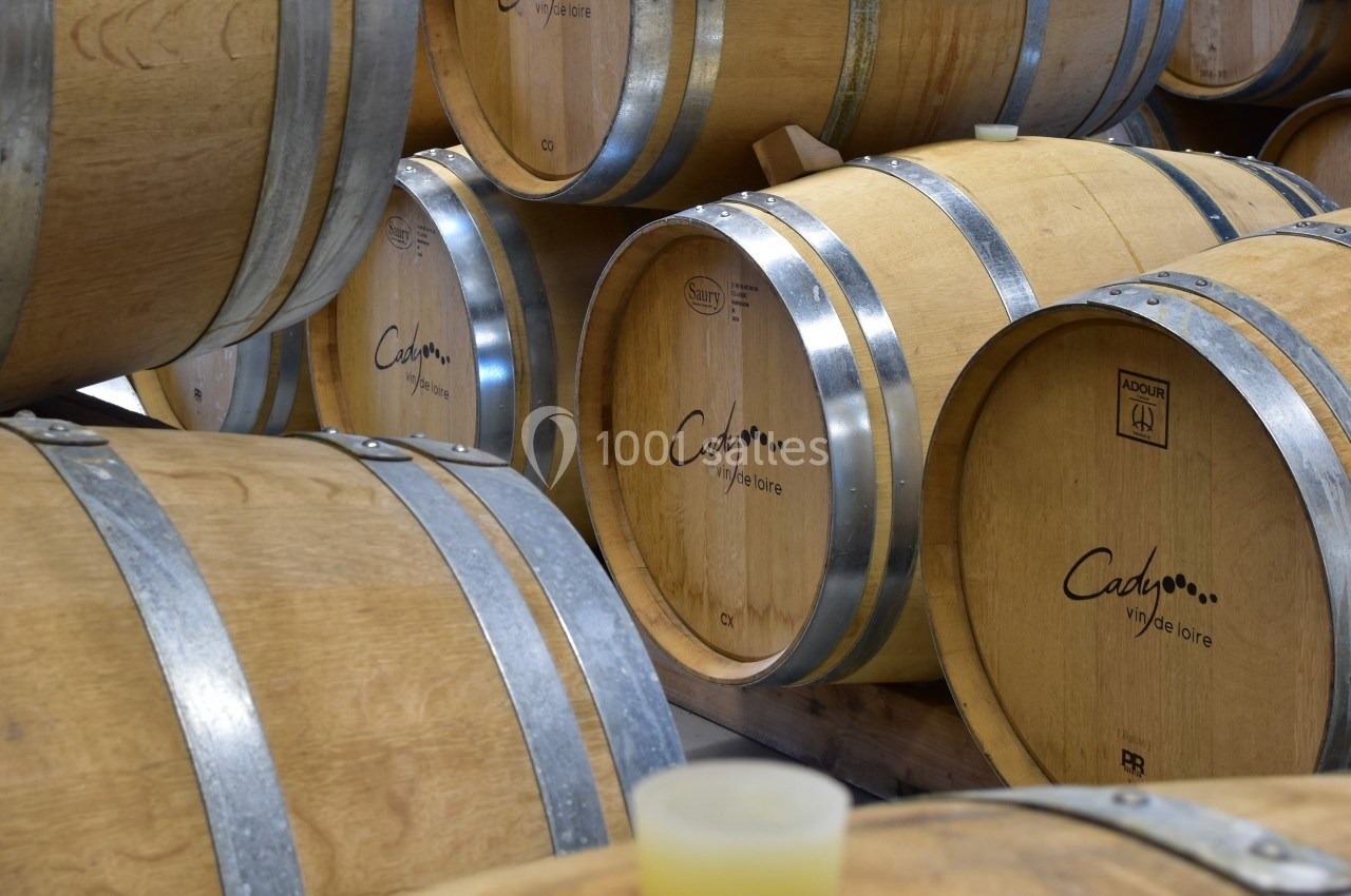 Fûts en bois empilés dans une cave, utilisés pour le vieillissement du vin.