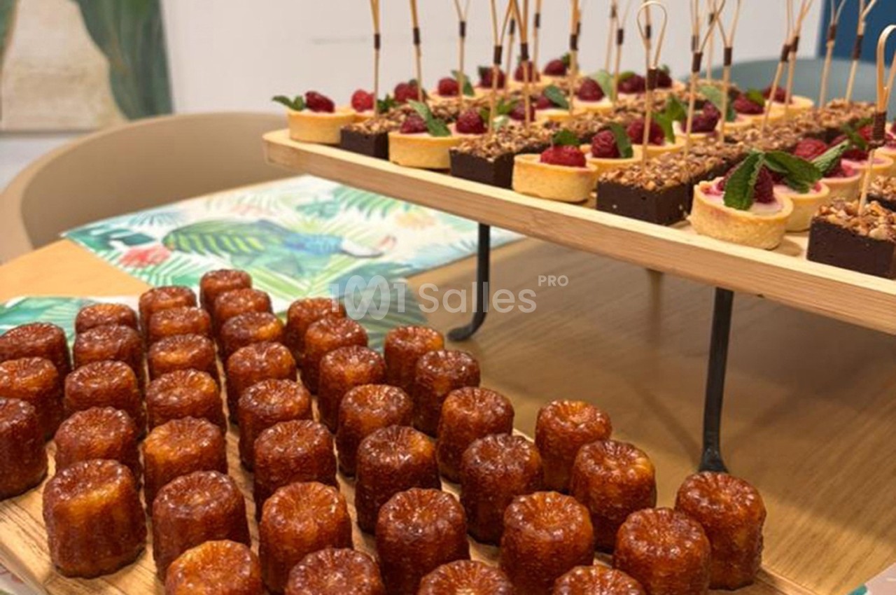 Plateau de cannelés et assortiment de desserts variés présentés sur une table en bois.