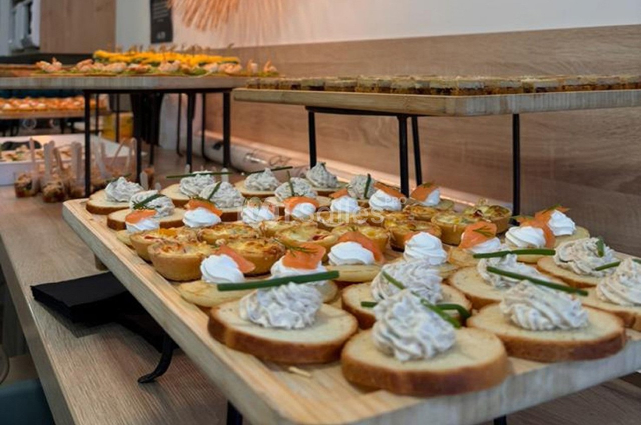 Plateau de toasts variés avec garnitures salées, disposés sur une table en bois dans un cadre de réception.