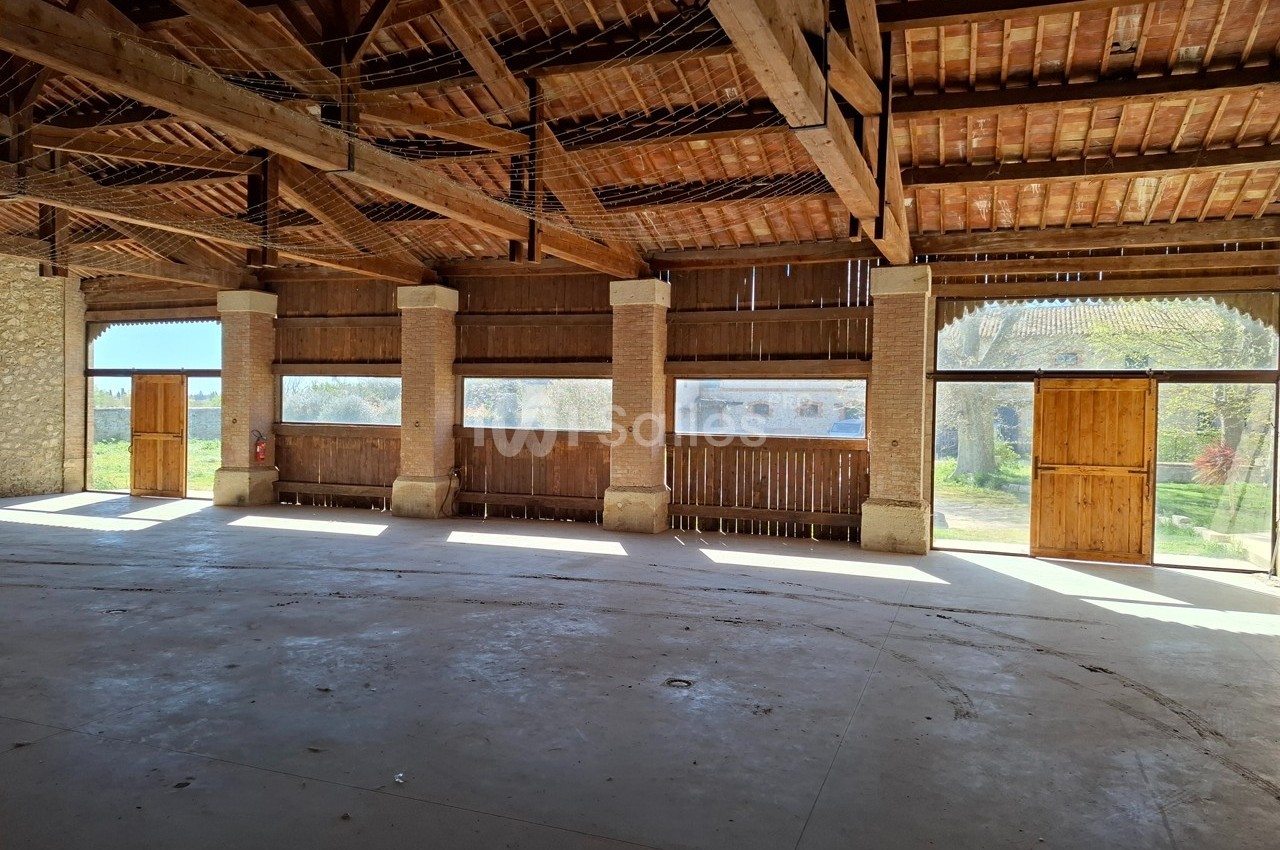 Intérieur d'une grange en bois avec des portes ouvertes laissant entrer la lumière naturelle.