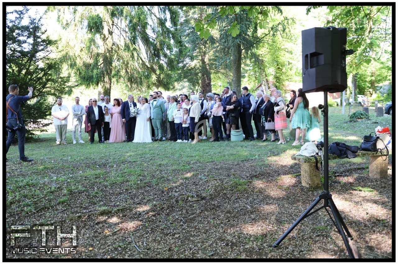 Groupe de personnes posant pour une photo de groupe en extérieur, entourées d'arbres et de verdure.