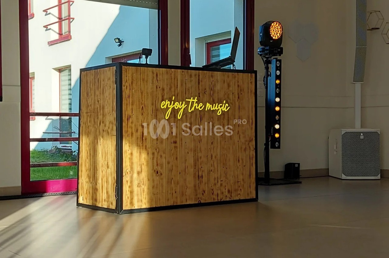 Console DJ en bois avec l'inscription lumineuse ’enjoy the music’, éclairée par la lumière naturelle dans une salle.