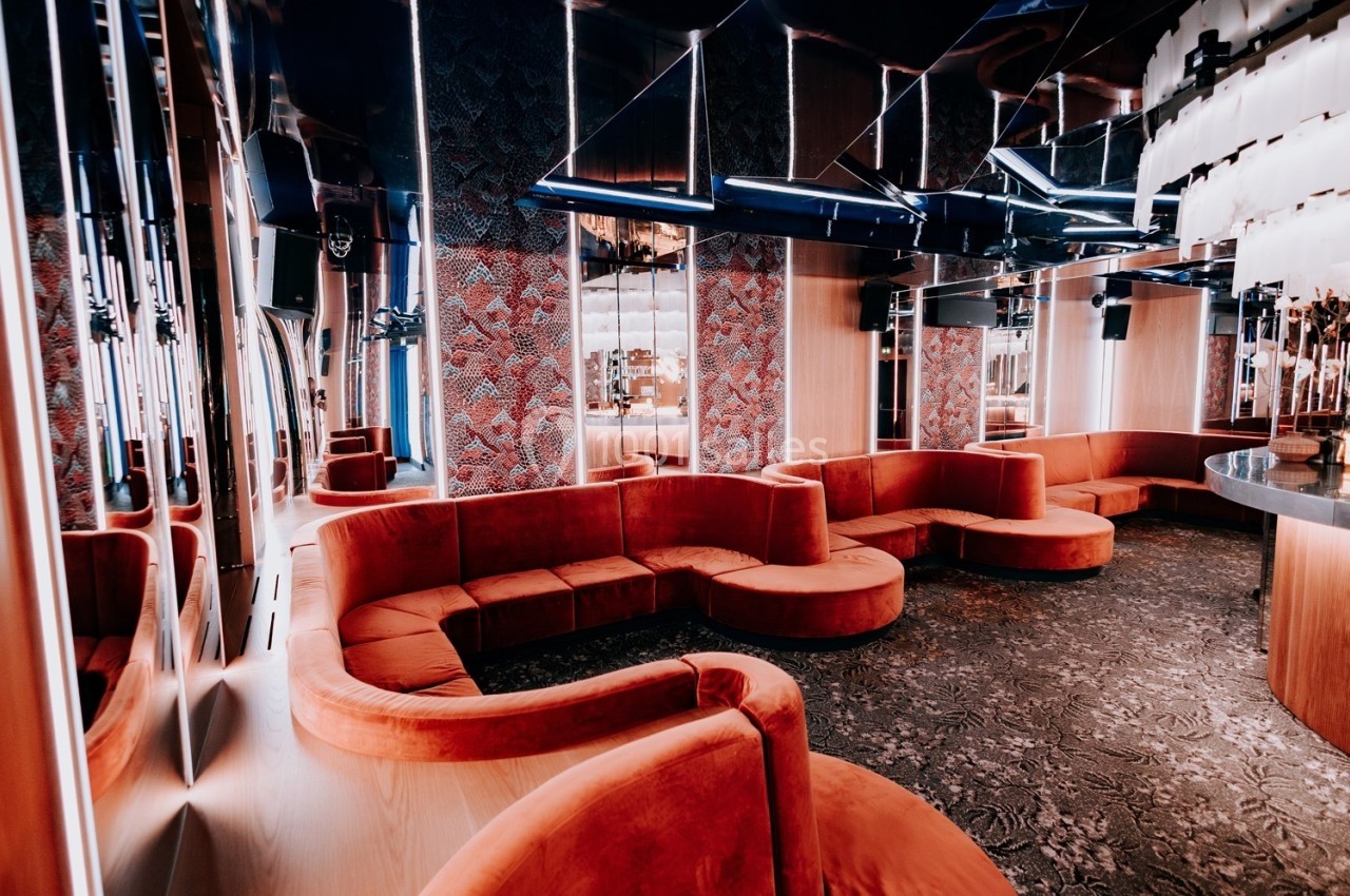Canapés rouges incurvés dans un espace intérieur moderne avec murs texturés, miroirs et éclairage design.