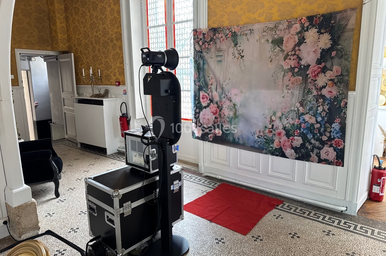 Un photobooth installé dans une pièce élégante avec un fond fleuri et un sol en mosaïque.