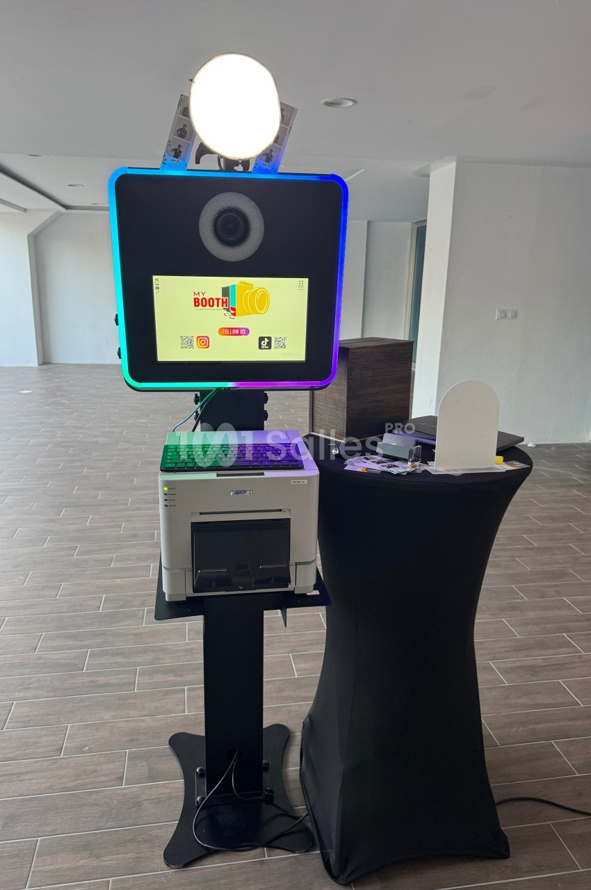 Borne photo interactive avec écran, imprimante et accessoires, installée dans un espace intérieur moderne.