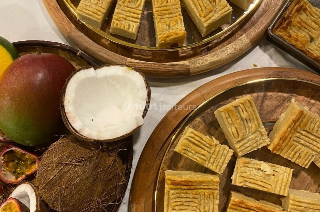 Assortiment de gâteaux sur des plateaux en bois, accompagnés de fruits tropicaux comme noix de coco, mangue et fruit de la…