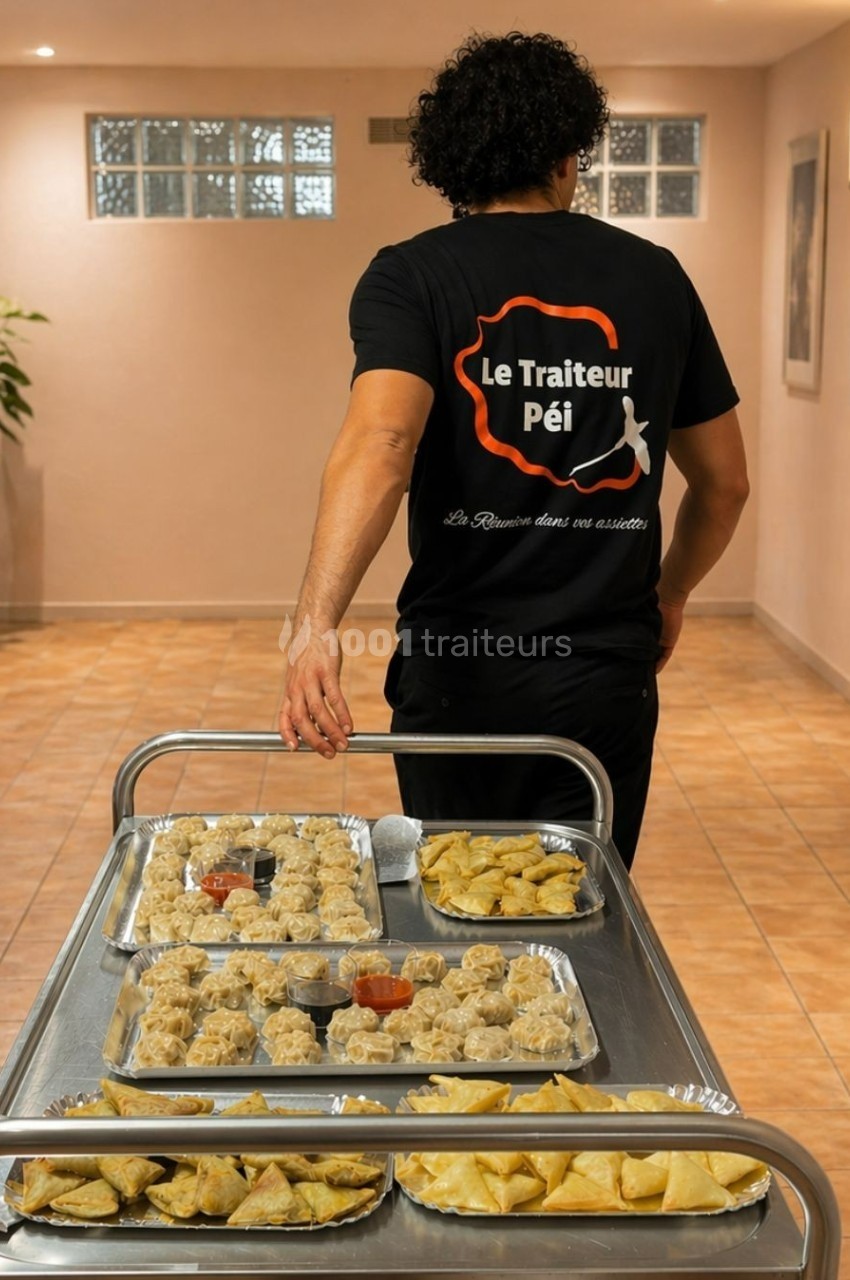 Un traiteur transporte un chariot rempli de plateaux contenant des bouchées et des amuse-bouches dans un couloir.