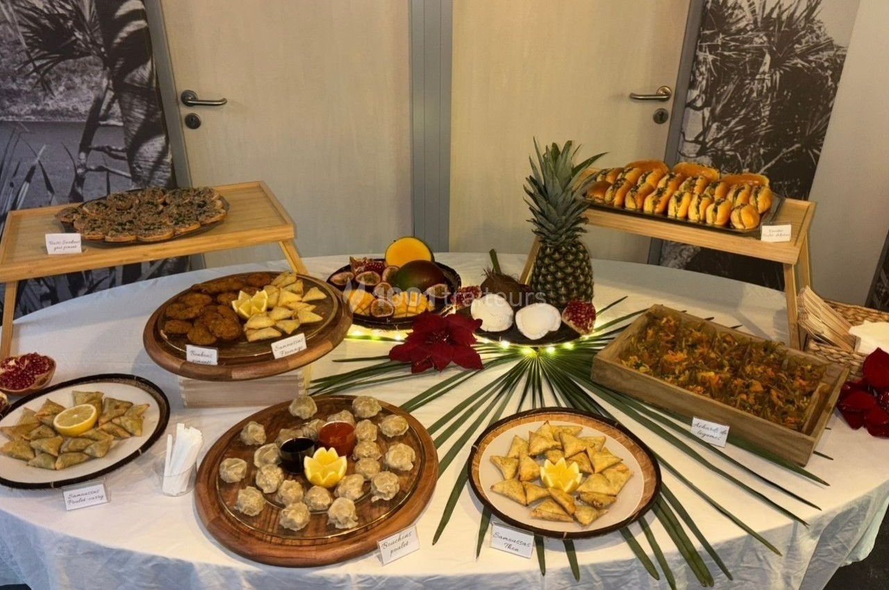 Table garnie d'un buffet varié comprenant des plats salés, des fruits tropicaux et des desserts, présentés sur des plateaux.