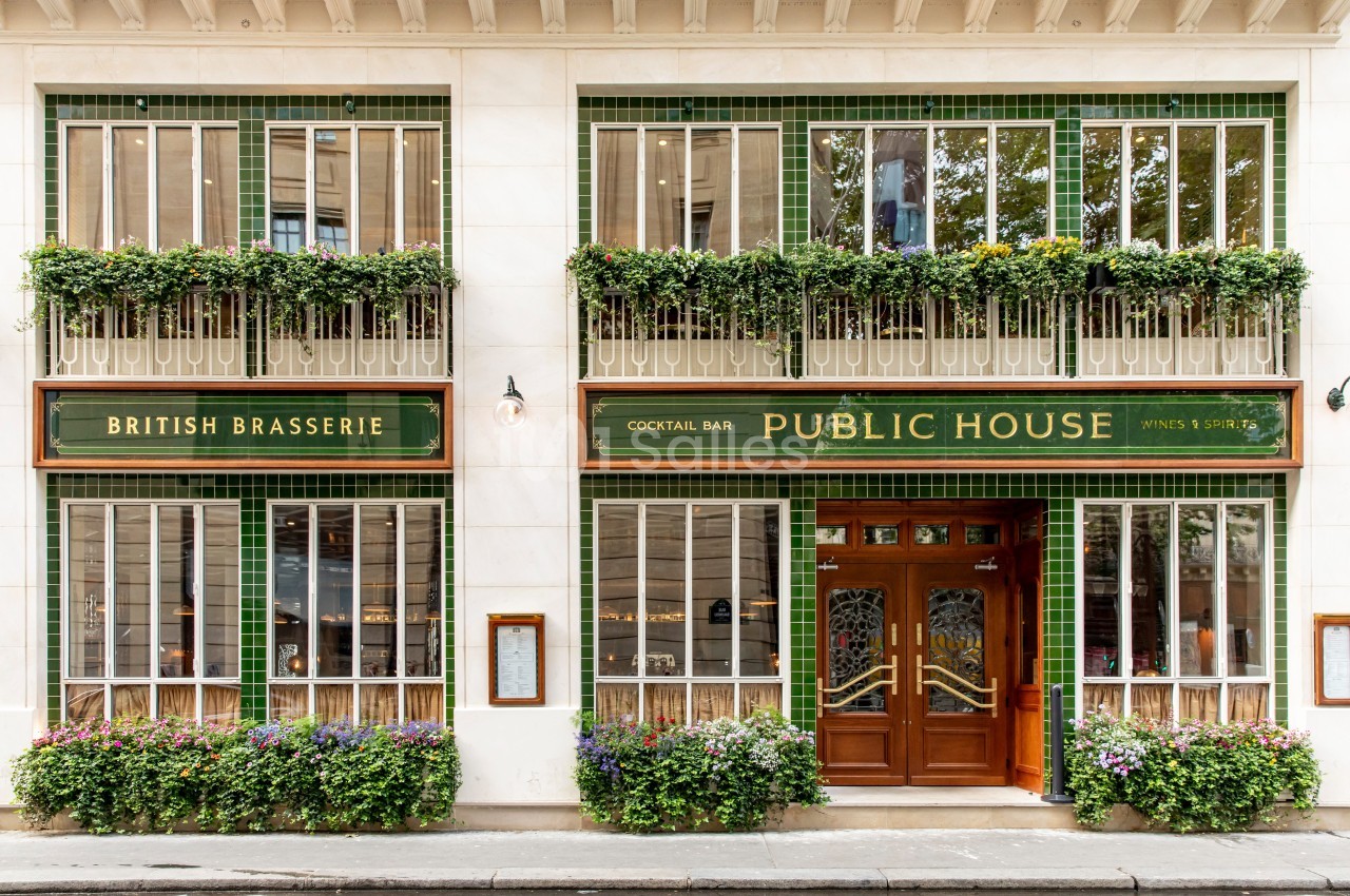 Façade d'un pub avec enseignes ’British Brasserie’ et ’Public House’, décorée de plantes et carreaux verts.