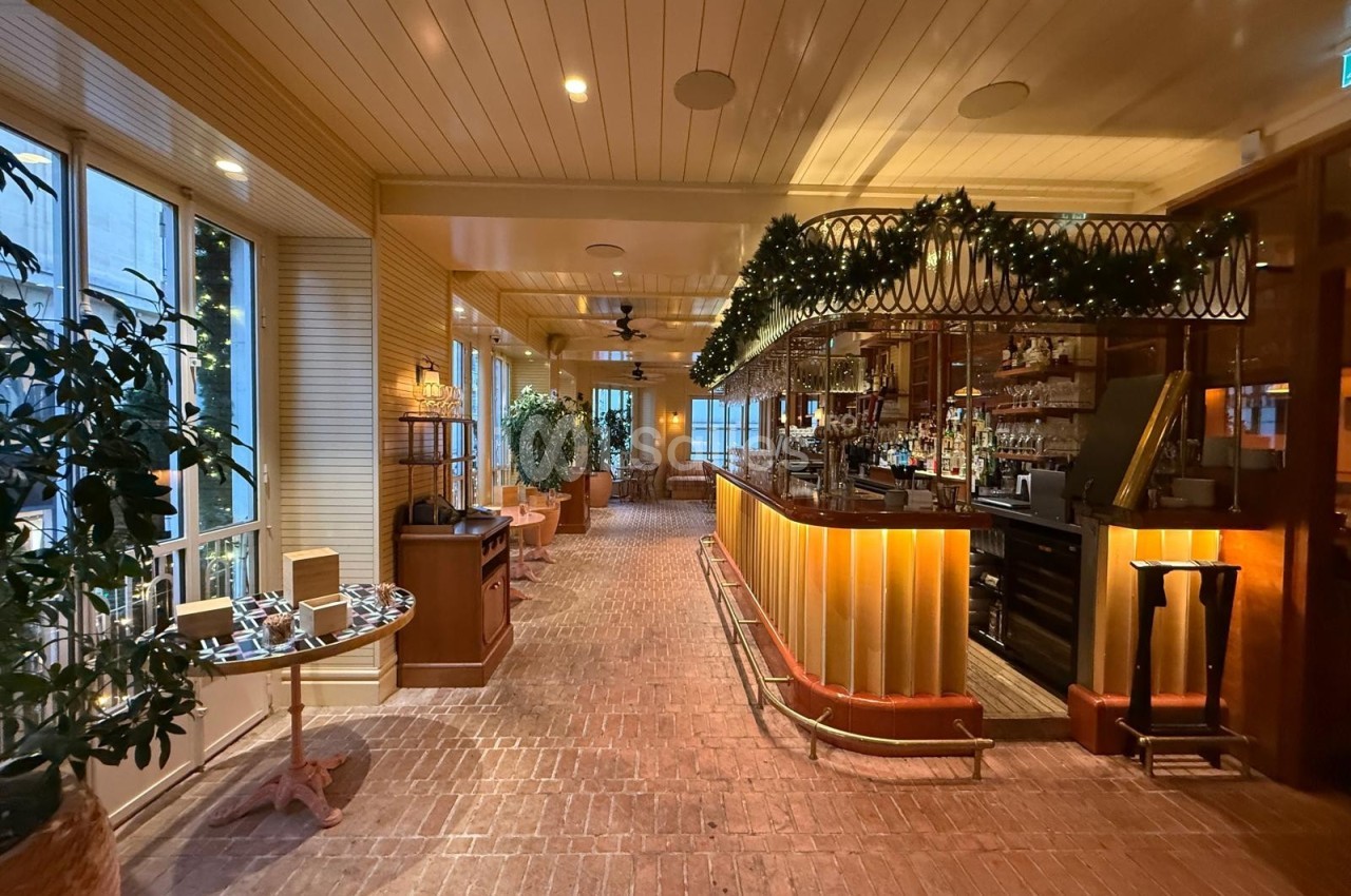 Intérieur d'un restaurant chaleureux avec bar éclairé, décorations lumineuses et plantes en arrière-plan.