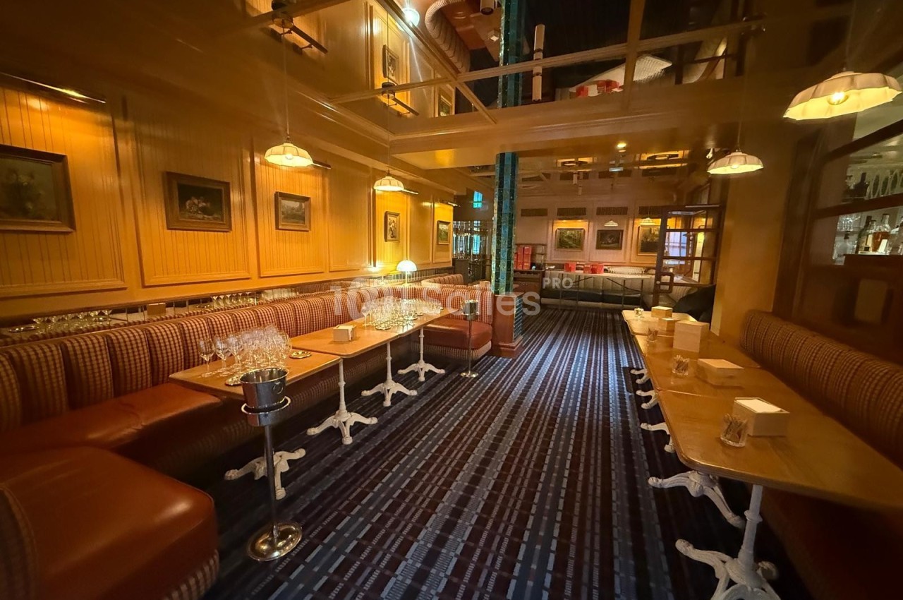 Salle de restaurant chaleureuse avec banquettes en cuir, tables dressées et éclairage tamisé.