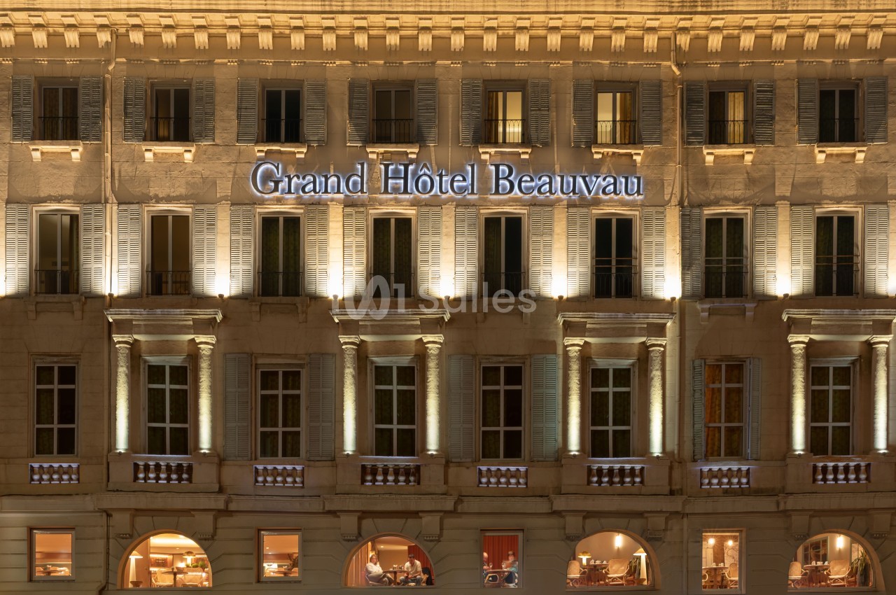 Façade haussmannienne du Grand Hôtel Beauvau éclairée la nuit - Pierre beige, rangées de fenêtres et colonnes.