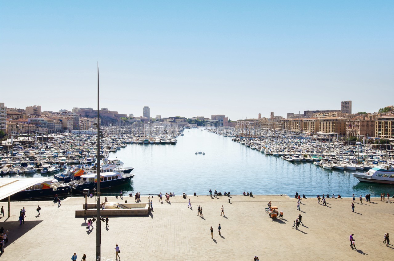 Port naturel de Marseille avec centaines de bateaux amarrés, quai piétonnier animé et immeubles Belle Époque.