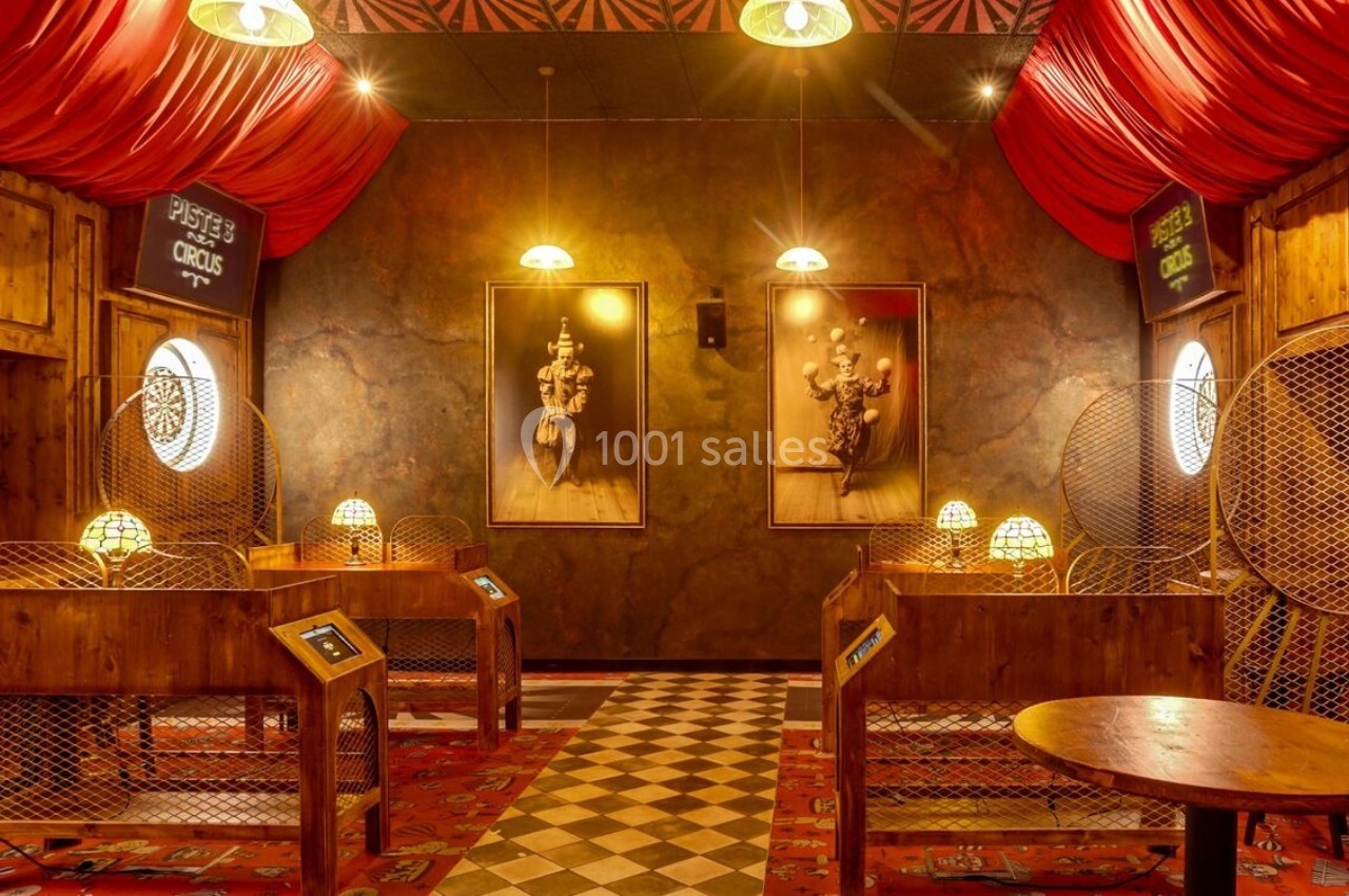Salle décorée sur le thème du cirque avec des stands en bois, des lampes colorées et des portraits rétro sur les murs.