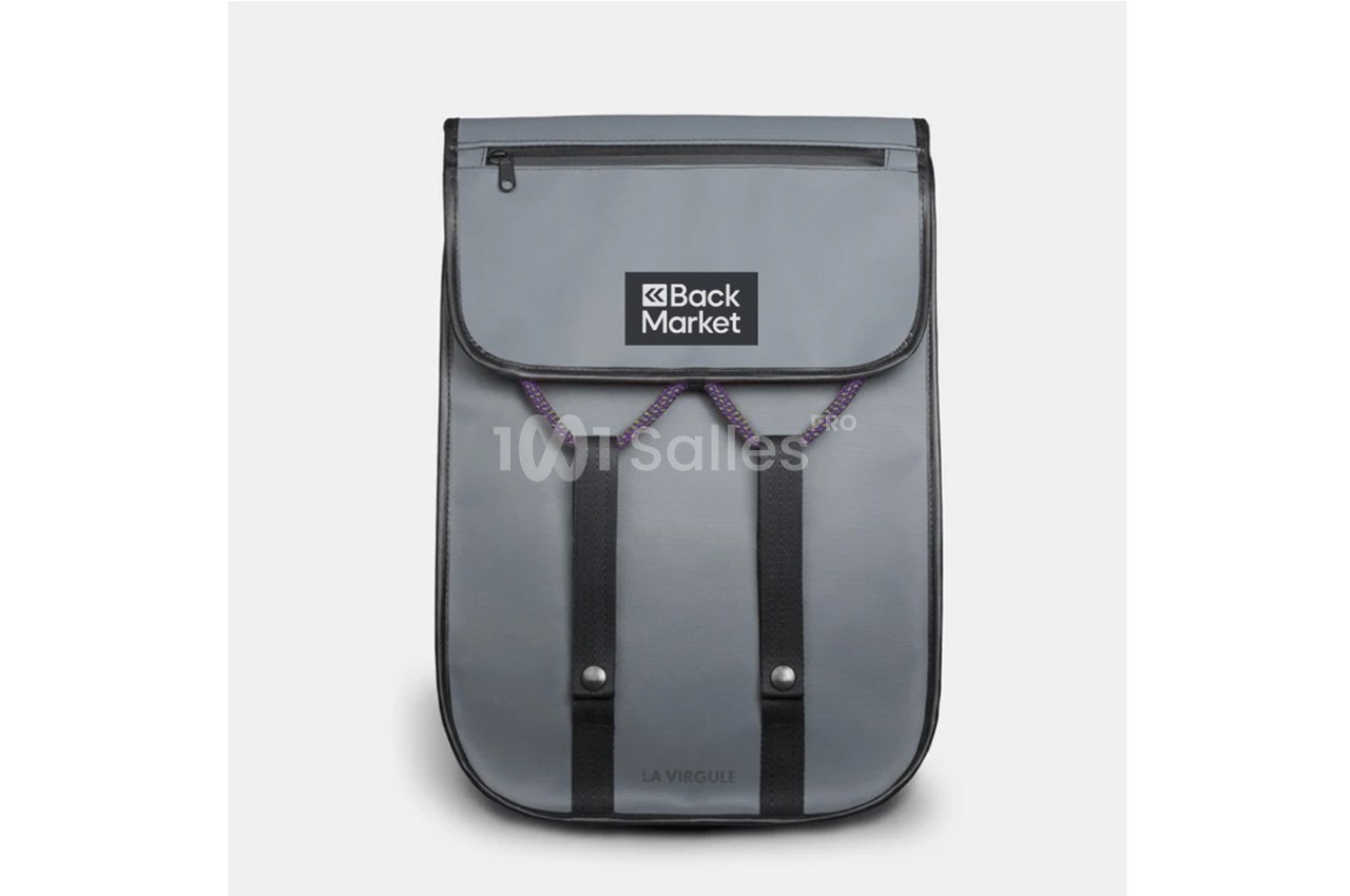Sac à dos gris avec rabat, logo ’Back Market’ visible, deux sangles noires et une poche zippée sur le dessus.