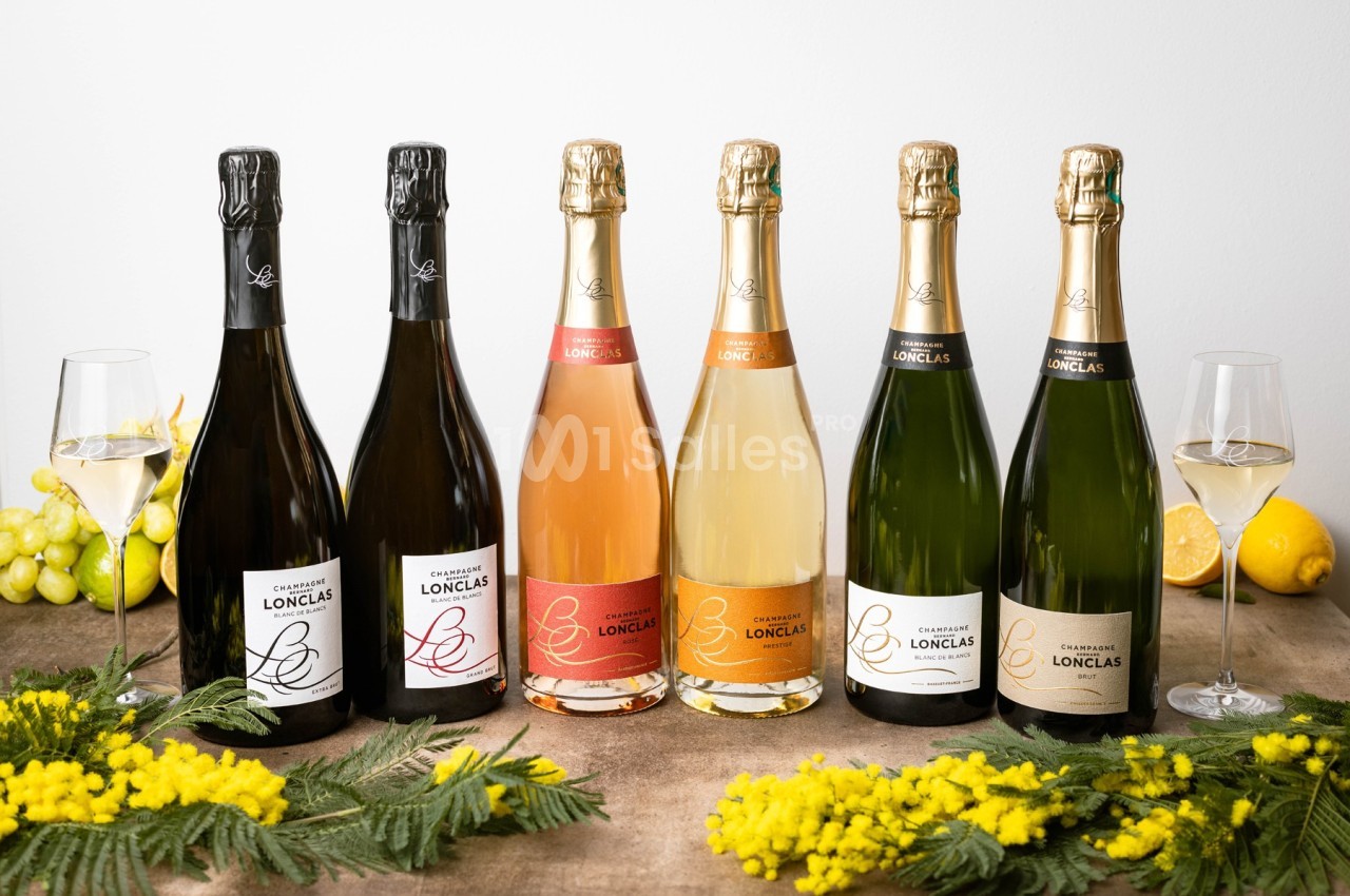 Bouteilles de champagne alignées sur une table avec des verres remplis, des grappes de raisin, des citrons et des fleurs en…