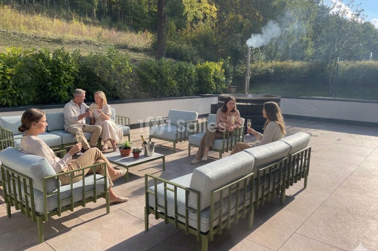 Personnes assises sur des fauteuils extérieurs, discutant et partageant un moment convivial sur une terrasse ensoleillée.