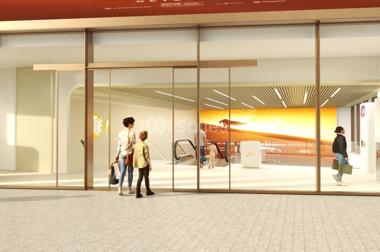 Entrée d'un espace moderne avec des portes vitrées, un écran lumineux et des personnes entrant ou sortant.