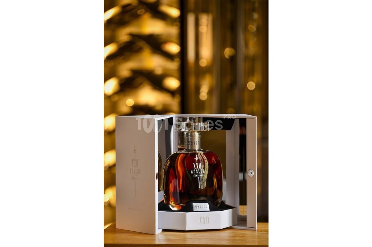 Bouteille de cognac XO présentée dans un coffret ouvert, posée sur une table avec un fond flou de cave à vin.