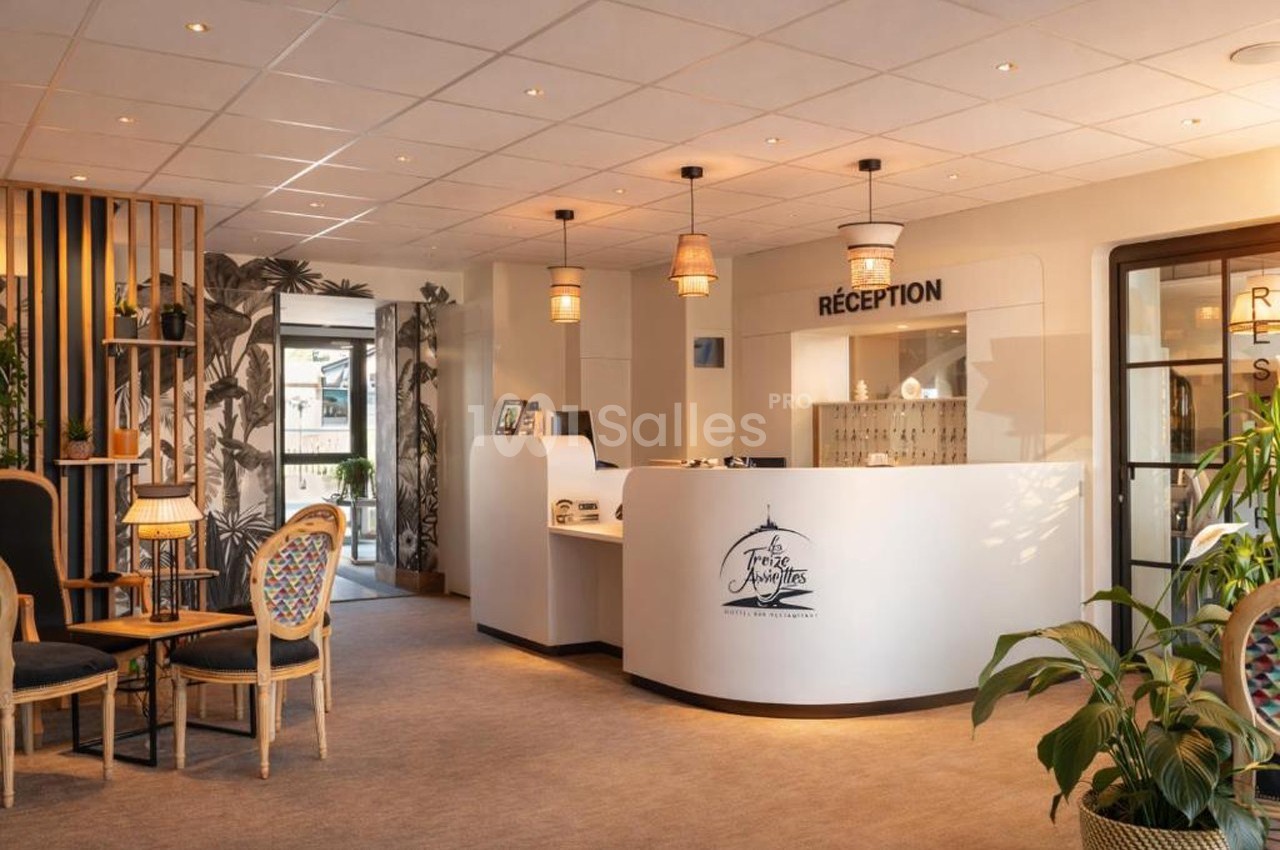 Réception d'un hôtel avec comptoir blanc, chaises en bois, plantes et éclairage chaleureux.