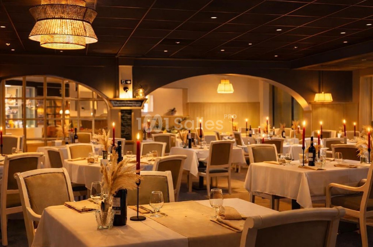 Salle de restaurant élégante avec tables dressées, chandelles allumées et éclairage tamisé.